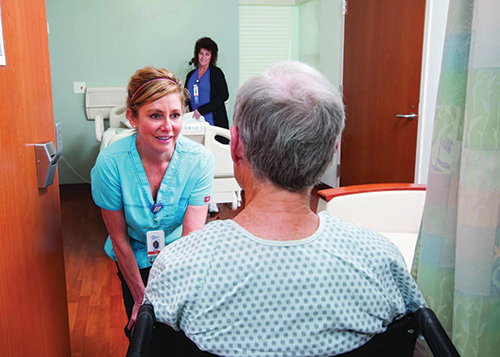 Nurse interacts with patient in hospital room.