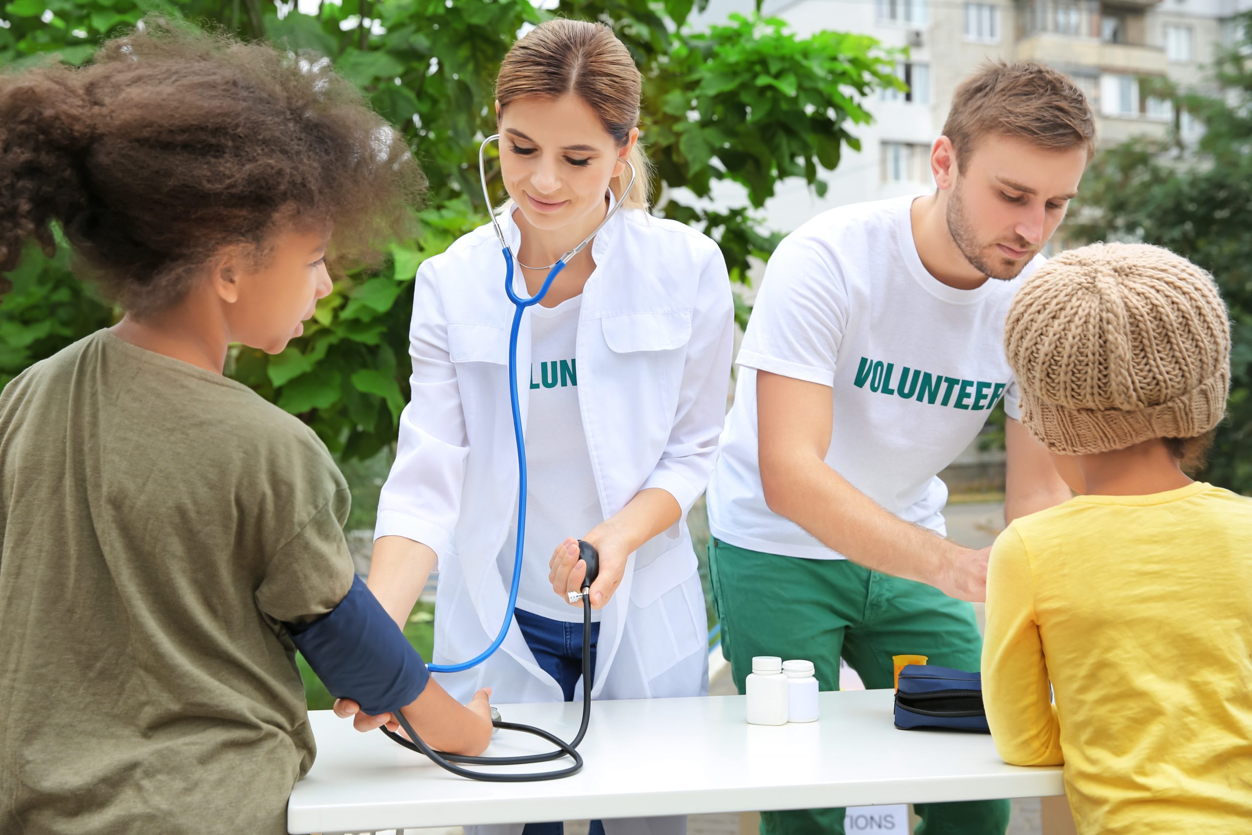 Volunteer doctor measuring blood pressure of poor African child outdoors