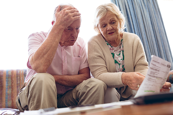 Senior couple discussing over medical bill while sitting on sofa