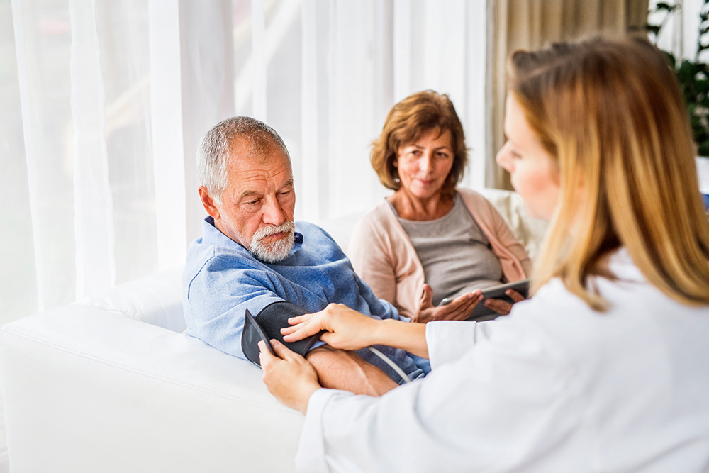 Female doctor checking blood pressure of senior man.
